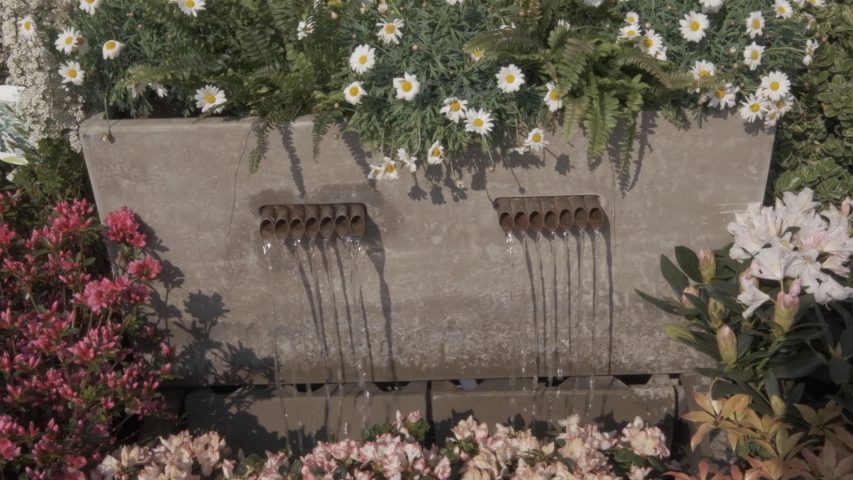 Garden water feature surrounded by flowers and bedding plants.