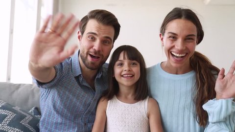 Happy family with daughter sitting on sofa make video call chatting with friends use electronic device web cam point of view waving hands greeting relatives online telecommunications modern tech users