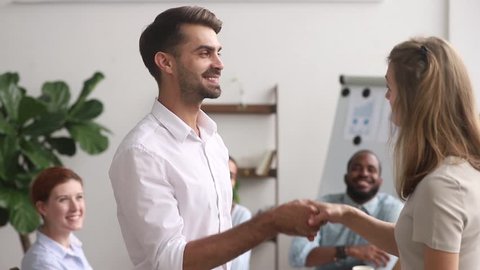 Multi-ethnic employees clap hands while boss greeting corporate client, happy businesswoman ceo congratulate shake hands successful worker getting reward or promotion, handshake as symbol of gratitude