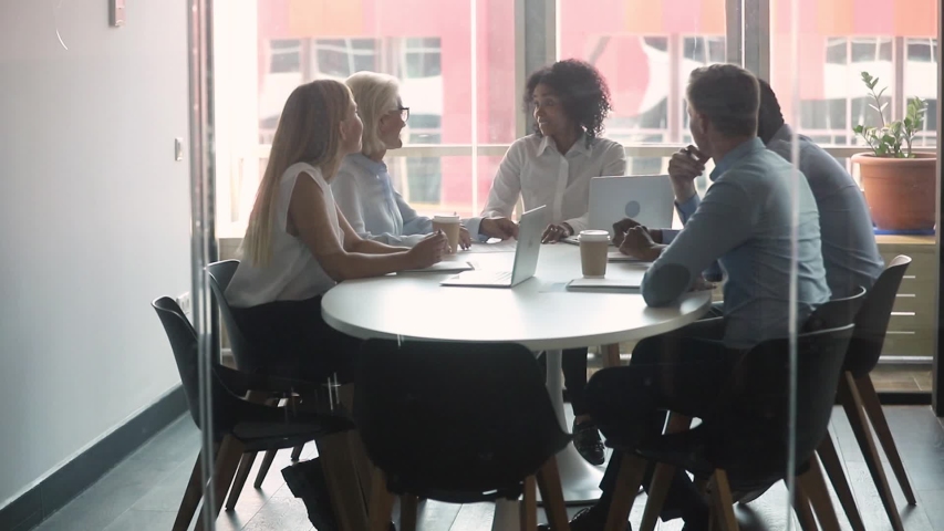 Multi-ethnic business partners gathered negotiate in boardroom behind closed doors view through glass, entities parties after discuss details of agreement signing contract shake hands feels satisfied Royalty-Free Stock Footage #1029333314
