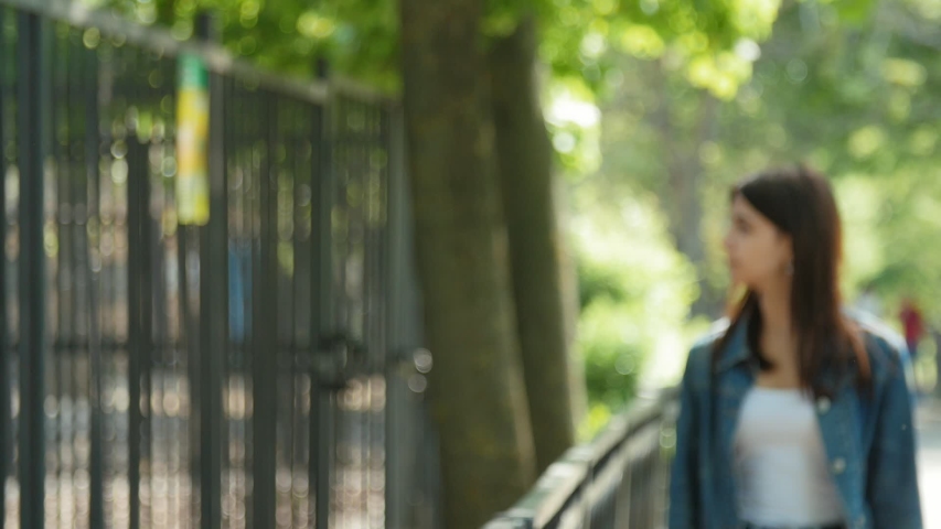 Positive tourist looking behing a fence in the zoo. Beautiful girl walking in the Zoo. Slow motion.