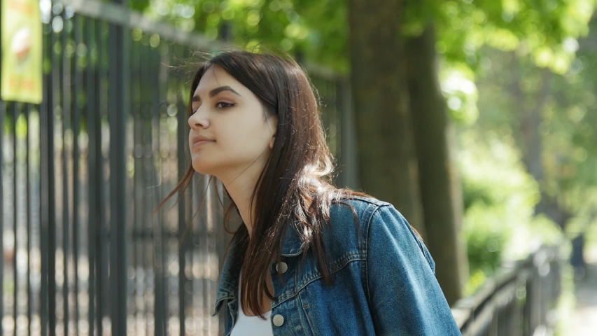 Positive tourist looking behing a fence in the zoo. Beautiful girl walking in the Zoo. Slow motion.