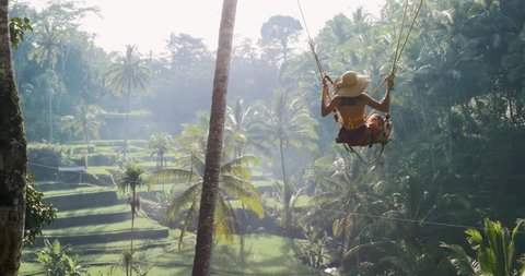 Beautiful girl swinging over the jungle in Bali