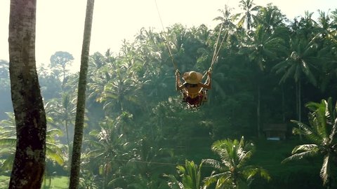 Beautiful girl swinging over the jungle in Bali