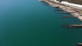 Aerial video shooting. Panoramic view of the black sea coast of Sochi Sunny spring day.Clear blue sea. Cars and trains go along the coast. The resort town of Russia. Breakwaters of stones on the shore