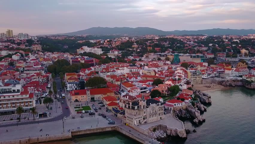 Aerial, drone shot, sideways over the coast of the atlantic sea, overlooking Palacio Seixas, Praia da Conceicao beach and more buildings, in Cascais bay, Portugal