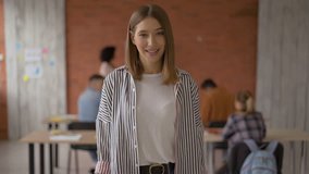 cheerful girl looks into the camera and shows gesture ok. student in the classroom. video 4K