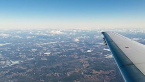 Video of flying at altitude with a jet wing visible above land and frozen lakes with wispy clouds in the late spring over New England.
