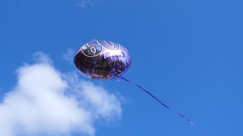 60th birthday helium balloon is flying against blue sky and white cloud