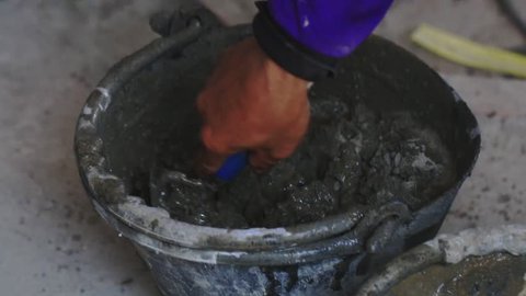 Male worker mixing cement concrete by hand with the bucket mixer.