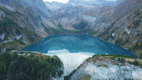 Water dam and reservoir lake aerial drone footage in Swiss Alps mountains generating hydro electricity power renewable energy and sustainable development