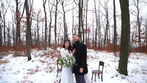 Wedding newlywed couple smiling looking at each other and at sky during outdoor ceremony during winter wedding snowy nature.
