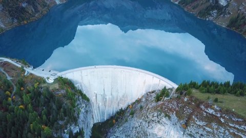 Water dam and reservoir lake aerial drone footage in Swiss Alps mountains generating hydro electricity power renewable energy and sustainable development. 4K 60fps video