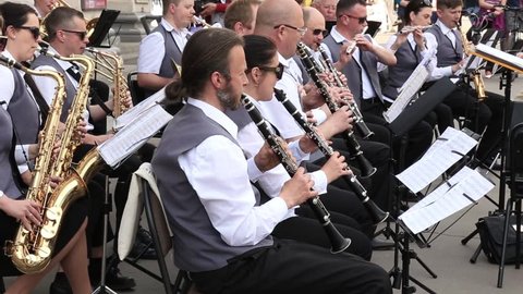 KRYVYI RIH, UKRAINE - MAY, 2019: People musicians sitting play wind instruments in municipal orchestra performing at festive concert open air.