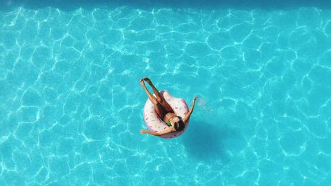 Girl in the pool swims on an inflatable donut of pink color