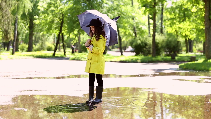 video of child playing and walking through a puddle in the park