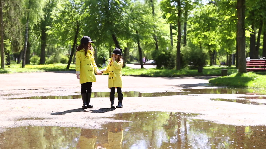 young girls running throught the puddles in the park after the rain