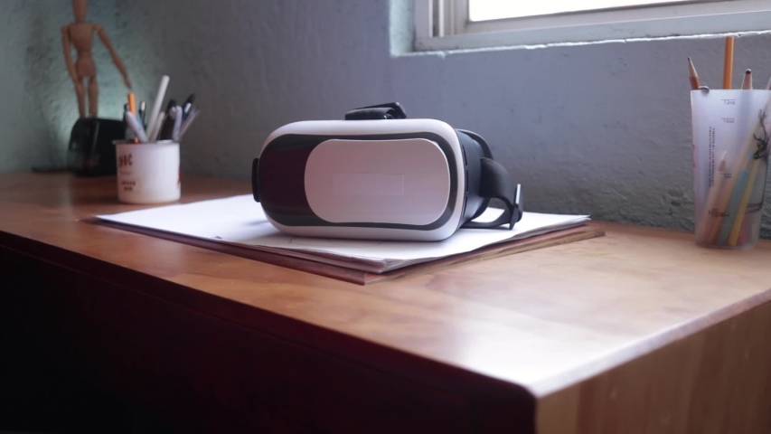 Front view. Male hand take a vr headset from wooden desk. Virtual reality for home. Virtual reality gadget to use with a mobile phone. 3d experience with a vr headset