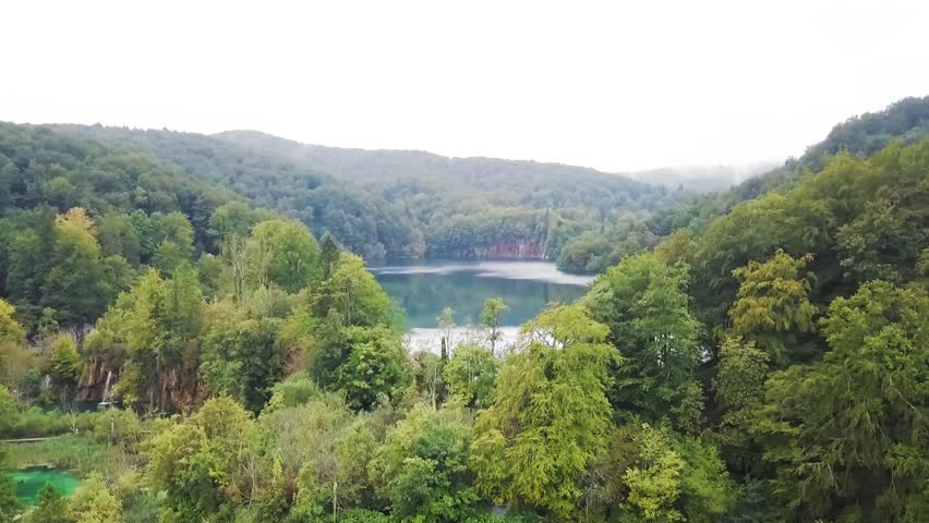 Aerial reveal, water flowing over untouched waterfalls and lakes of Plitvice Lakes National Park, Croatia