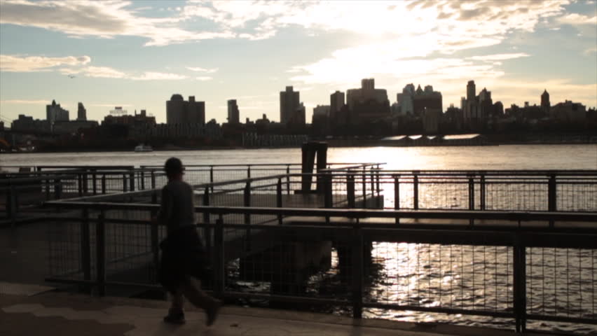 Slow motion joggers on the East River Bikeway at sunset in New York