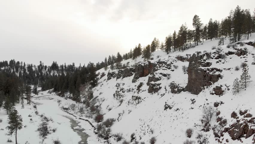Drone Aerial of Frozen Stream Under Hills Covered With Winter Snow in Palouse Region Washington State USA. Landing Shot