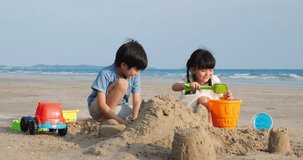 Asian kids brother and sister playing build pile of sand on the beach summer together in holiday. Concept of family, travel and relationship. 4k resolution.