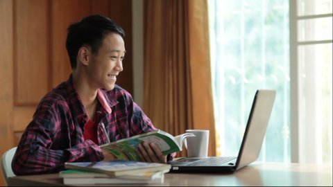 Asia Teenage boy studying online on laptop with smiling and fun face at home. online education and e-learning concept.