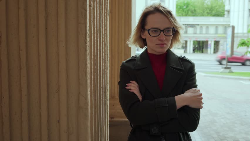 Unhappy woman with arms crossed turns and looks into camera at city street