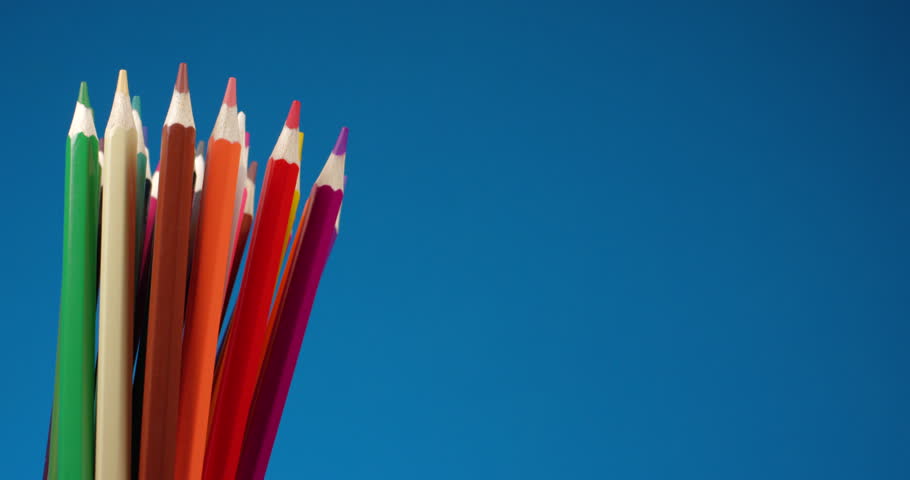 Set of multi-colored pencils rotating on a blue screen, chromakey background. Extreme close up view