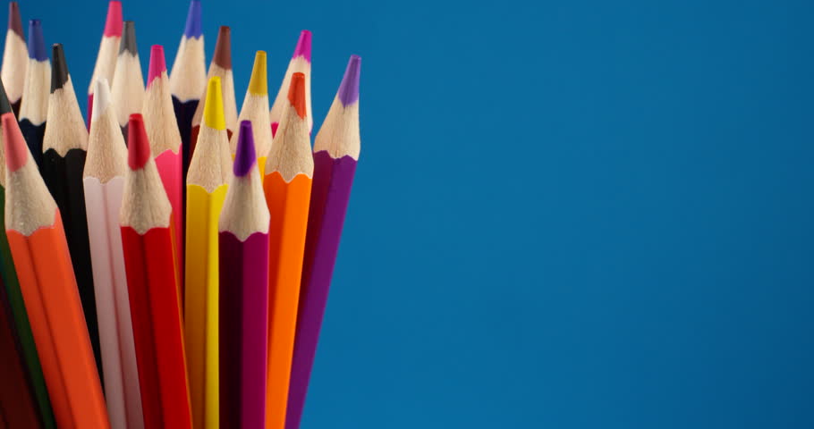 Set of multi-colored pencils rotating on a blue screen, chromakey background. Extreme close up view