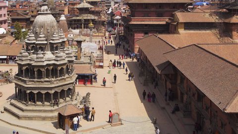 Locals and tourists walking on Durbar Square, in ancient capital of Nepal - Patan. Buildings in construction scaffold which restore after an earthquake are visible. Nepal, Kathmandu, on March 7, 2017