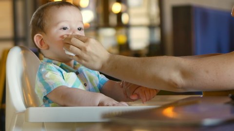 Mom Wipes Her Mouth and Hands at the Adorable Baby. A Charming Child Laughs and Claps. Cute Little Baby Eating Her Dinner. 4k.
