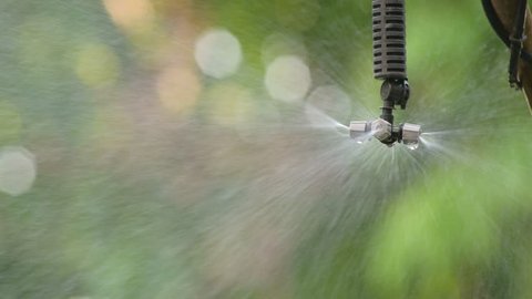 Close up sprinkler head when turn on - off pipe valve, sprayer spray water drop on blur bokeh background, plant watering system.