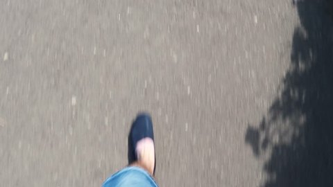 Walking down a concrete street from first person point of view (POV) wearing denim shorts in the summer