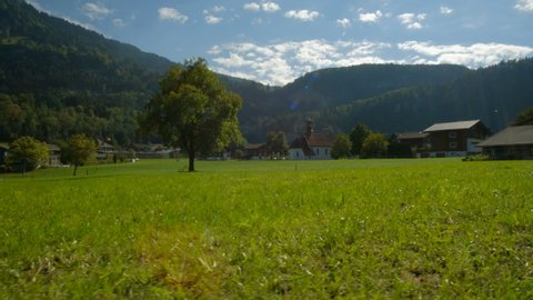 Walking past beautiful fields of green farmland and Swiss houses in the town of Lungern in Switzerland.