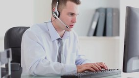 Close up of a Caucasian businessman talking on a headset while typing on his computer in an office. Beside him is a digital animation of a light bulb shaped globe lighting up. - Powered by Shutterstock - Get 15% off with code: PIKWIZARD15