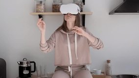 Caucasian girl watching 360 video at home, wearing VR headset. Pretty woman touch something using modern virtual reality glasses at home on a sunny day. Innovative technology. Future is now