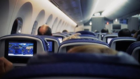 Passengers in comfortable seats of aircraft with the maps on screens in chairs 