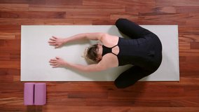 Top view of young woman doing Yoga exercise at home rolling up from Child's Pose.