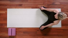 Top view of young woman doing Yoga exercise at home rolling down into Child's Pose.