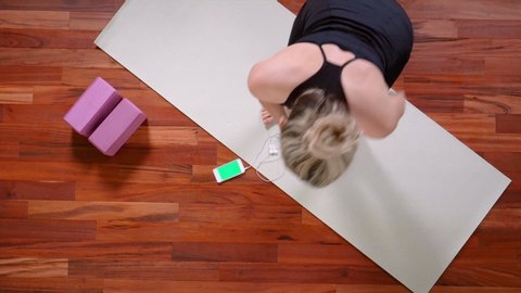 Top view of young woman walking away after Yoga exercise leaving Smartphone on the mat.