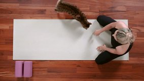 Top view of young woman doing Yoga exercise at home lying down in Child's Pose. Cat walks by