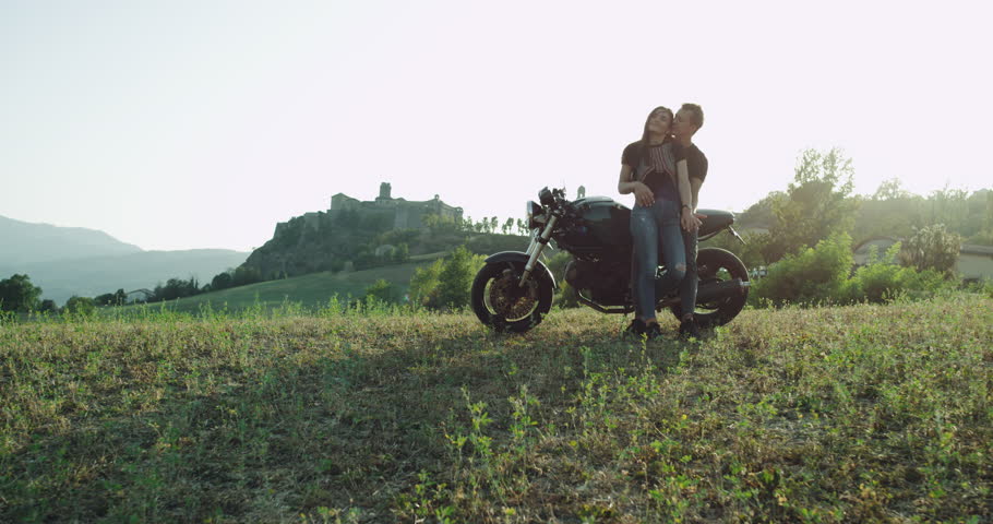 Beautiful couple sitting on the motorcycle stopped to enjoying the landscape view of nature, they hugging each other and lovely speeding time together | Shutterstock HD Video #1029423566