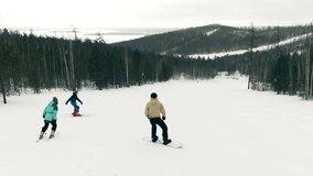 Mountain ski resort, aerial video. Skiers and snowboarders training in winter, skiing slope with fresh snow. 