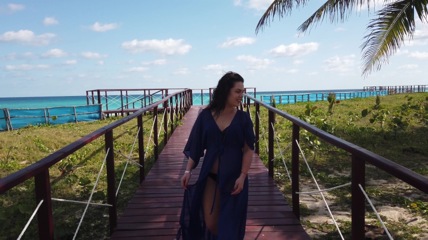 Girl on a wooden bridge in Varadero on their way to a white tropical beach and turquoise ocean
