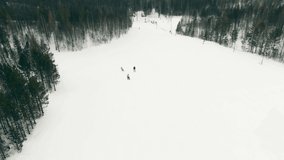 Mountain ski resort, aerial video. Skiers and snowboarders training in winter, skiing slope with fresh snow. 