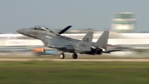 Zhukovsky, Russia, August 16, 2011. Fighter F-15 Eagle lands on runway. Dark gray plane with raised nose taxis on two main chassis. At end of runway, plane lowers its nose to front landing gear.