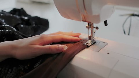 Closeup shot of female hands working on sewing machine. Young woman using a sewing machine at home or in workshop. Skillful expert tailor works on sew machine with silk or cotton. స్టాక్ వీడియో