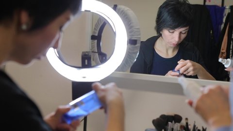 Young woman looks at the bottle, reflected in the mirror. 
Testing cosmetics in humans. Health risk for volunteers. Alternatives to animal testing.
