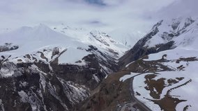 Paraglider flies among the snow-capped mountains. Video shot by drone